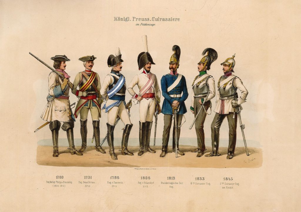 Mehrfarbiger, einseitiger Druck im Querformat. Motiv: Gruppe von 7 Männern in Uniformen der verschiedenen Regimenter der Preußischen Cuirassiere (frz. für Kürassiere) im Zeitraum von 1700 bis 1845 in der Felduniform. Dazu unter Bild Text: "1700 // Reg. Markgr. Philipp v. Brandenbg. // (1806 No. 5)", "1731 // Reg. Gens dArmes. // No. 102, "1786 // Reg. v. Panneweitz // No. 8", "1806 // Reg. v. Holzendorf // No. 9", "1813 // Brandenburgisches Cuir. // Reg.", "1833 / 8 tes Cuiassier Reg.", "1845 // 2 tes Cuirassier Reg. // gen. Königin". Am unteren rechten Rand der Zeichnung Signatur "E. Rabe"; mittig unter dem Bild Text: " Verlag u. Druck v. L. Sachse & Co Berlin".